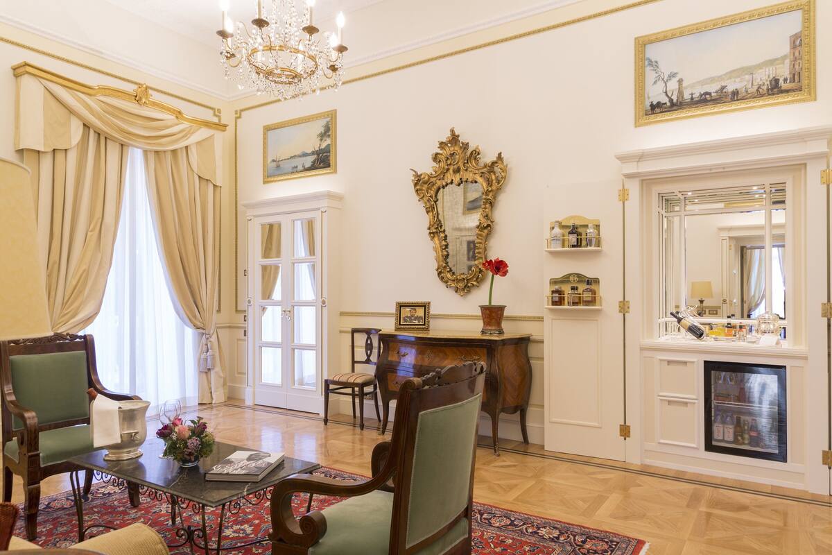 Una sala elegante con candelabro, chimenea y espejo.
