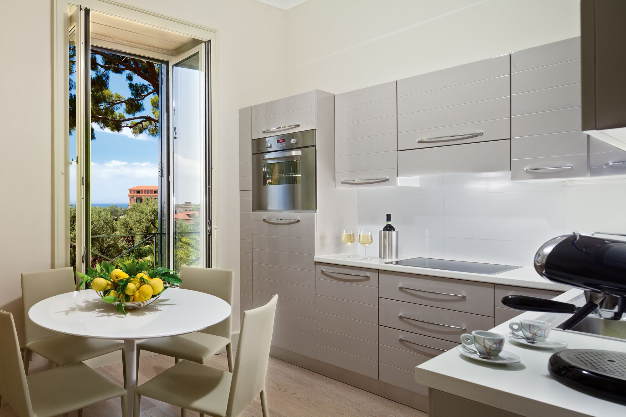 Una cocina moderna con comedor, que cuenta con un amplio ventanal con vistas a árboles y edificios.