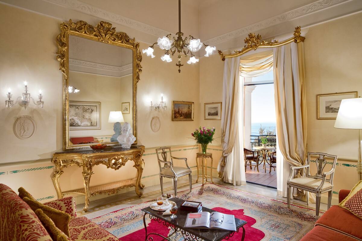 Una habitación lujosa con un espejo grande y decorado, una araña y vistas al exterior.