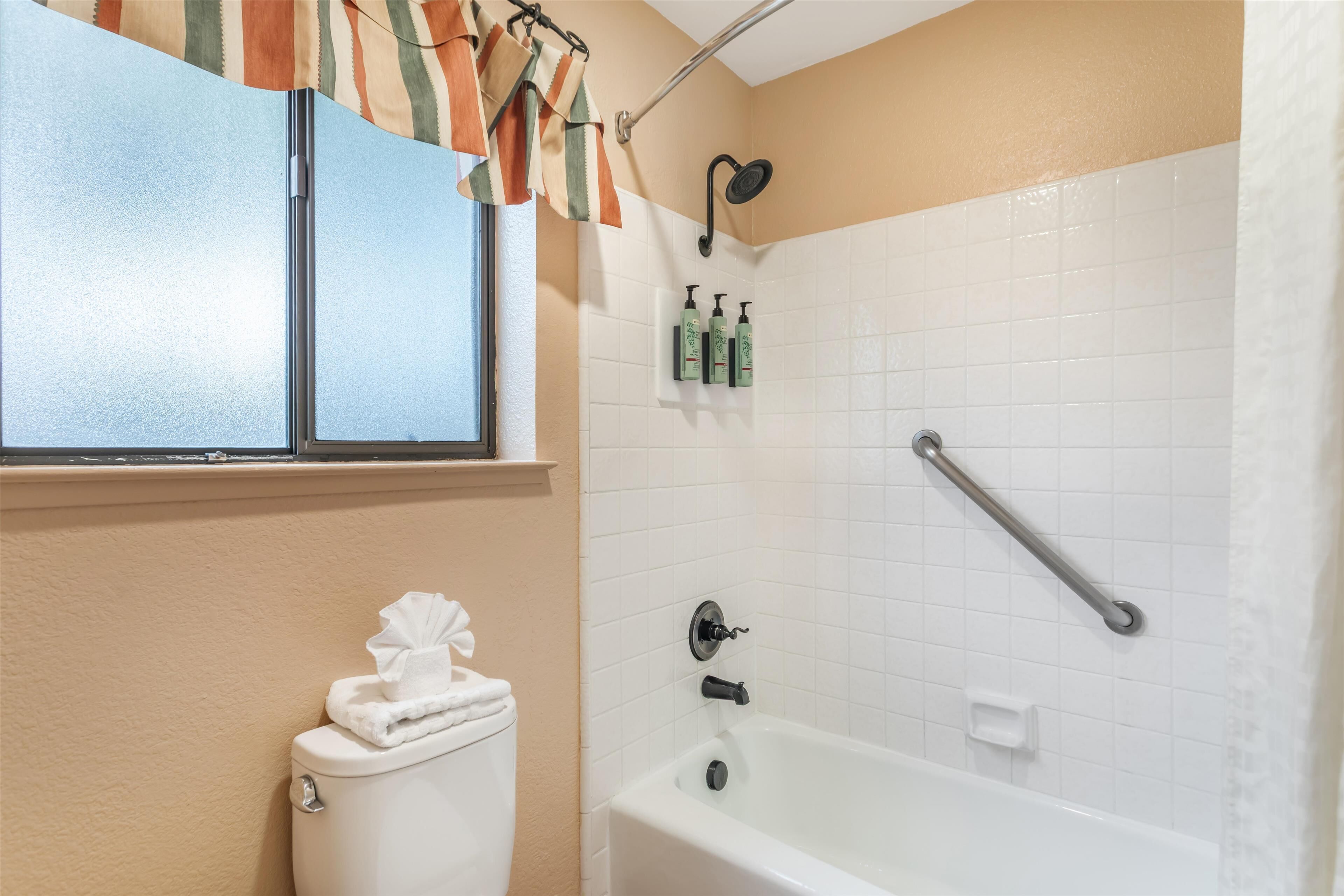 A bathroom with a toilet, a bathtub, and a window.
