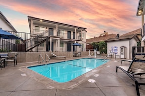 Relax by the rooftop pool surrounded by lounge chairs and umbrellas.