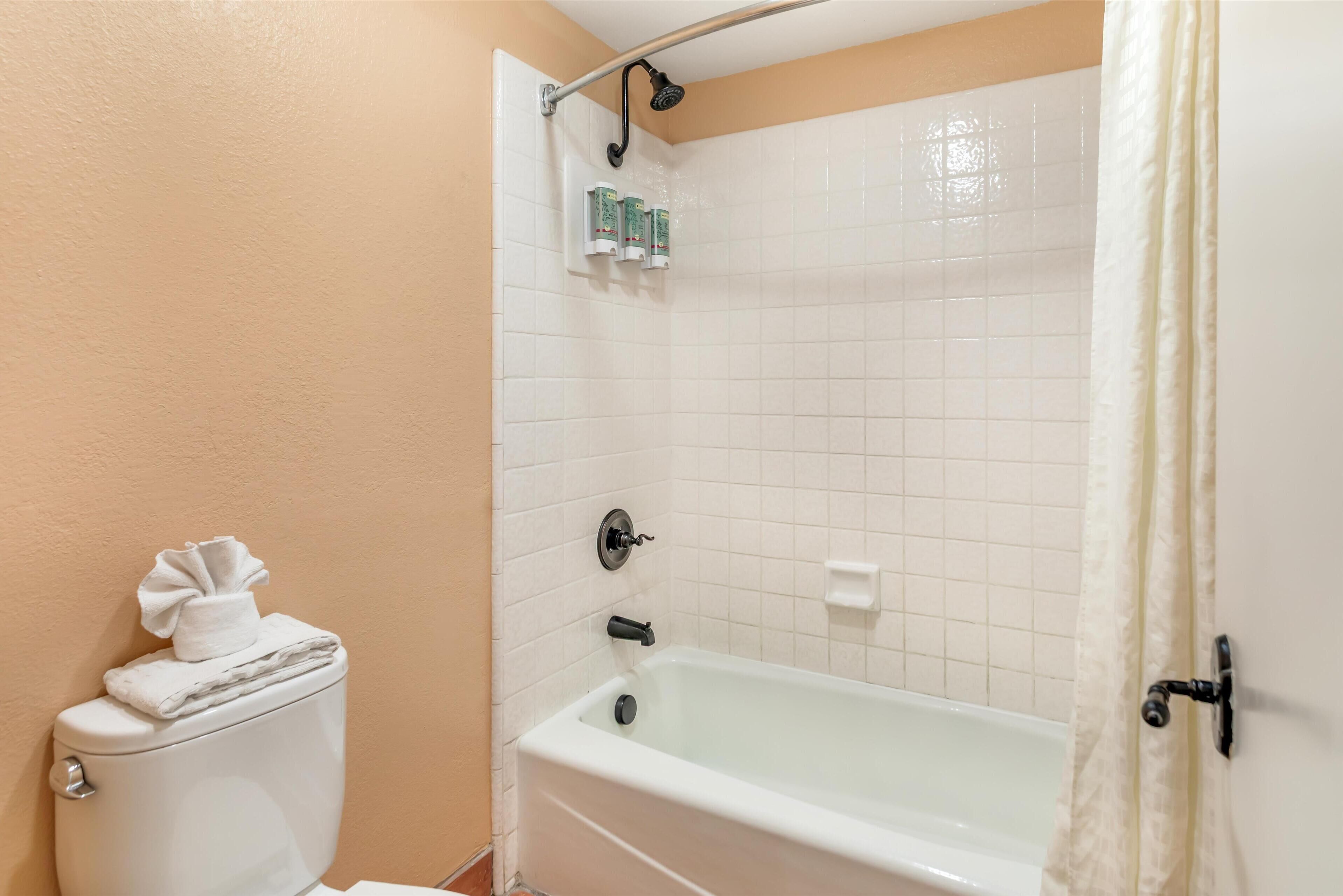 A bathroom with a toilet, a bathtub, and a showerhead.