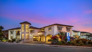 A hotel with a central entrance, a covered driveway, and a parking area. - Best Western Rose Garden Inn (Watsonville)