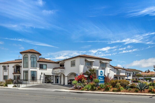 A two-story hotel with a Mediterranean architectural style, featuring arched windows and a tiled roof.