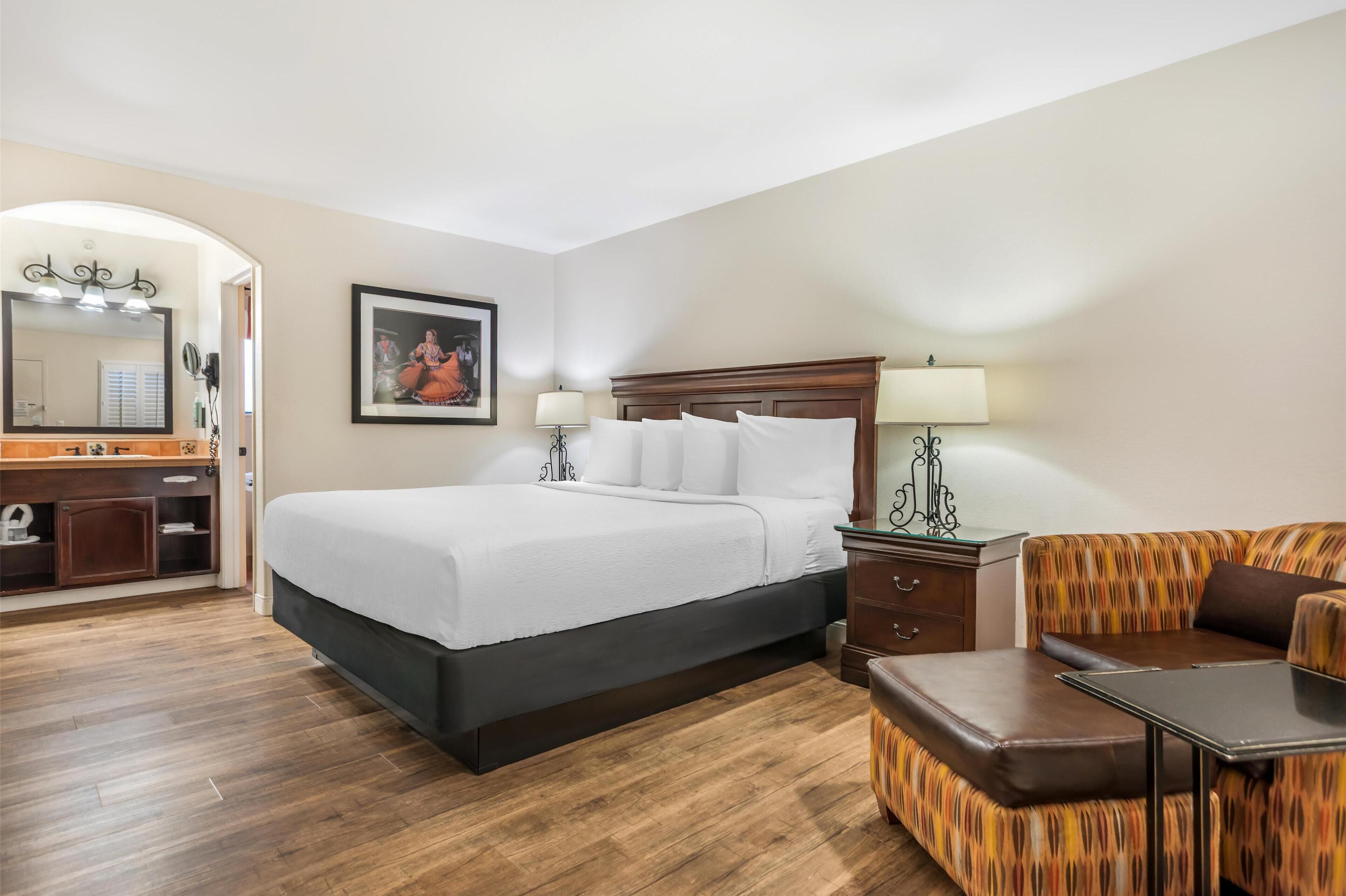 Una habitación de hotel con una cama, una tocador con espejo, un aparador, un sofá y una mesa.