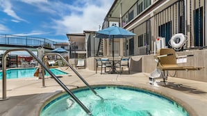 A swimming pool area with a diving board, lounge chairs, and a lifebuoy. - Best Western Rose Garden Inn (Watsonville)
