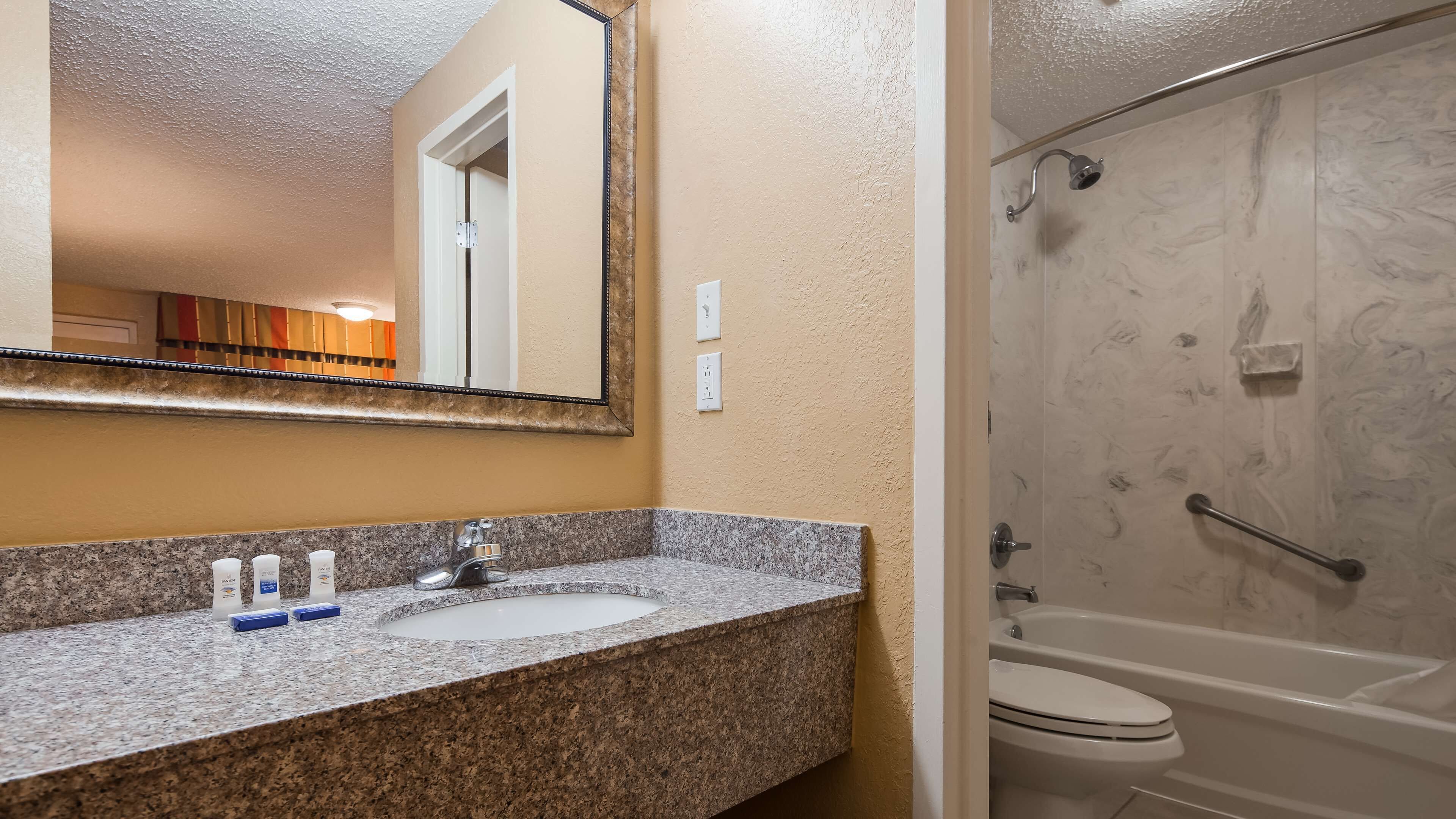A bathroom with a granite countertop sink, a mirror, a shower with a glass door, and a bathtub.
