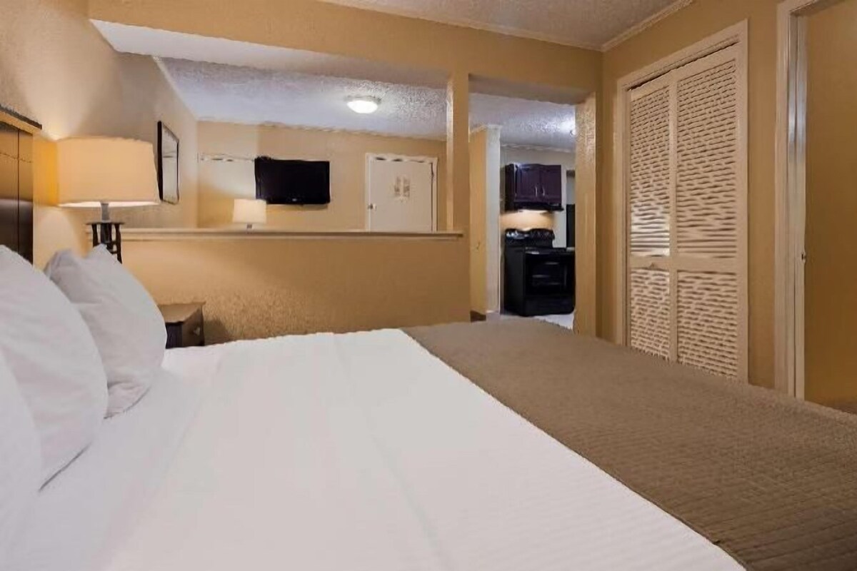 A hotel room with a bed, a desk, a television, and a bathroom with a shower and toilet.