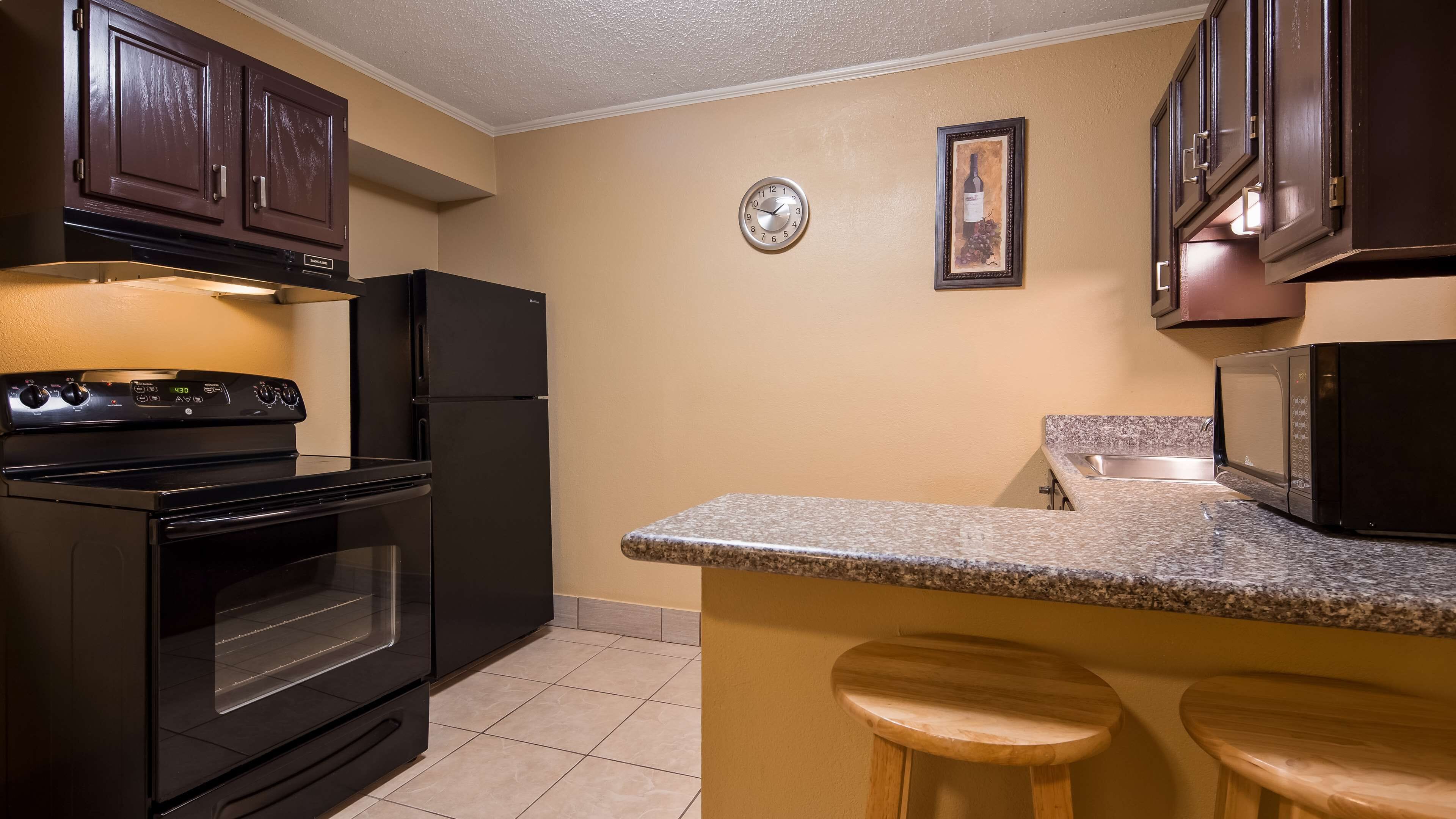 A kitchen with a stove, oven, microwave, and wooden stools.