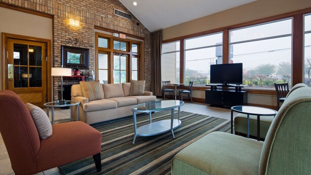 Un salón espacioso con pared de ladrillo, chimenea, sofá, mesa de centro y televisor.