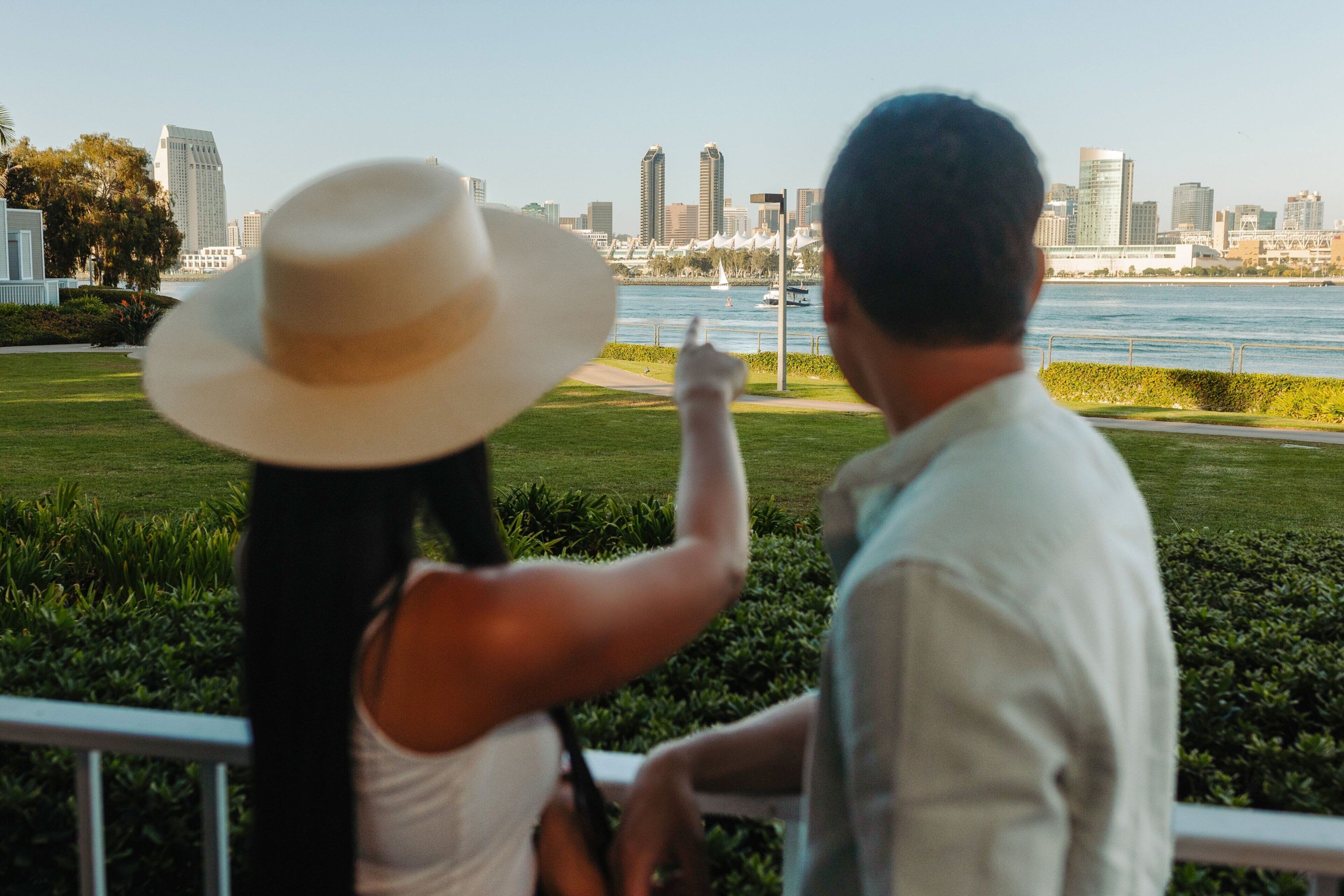 Una pareja contempla el horizonte urbano con un río y vegetación en primer plano.