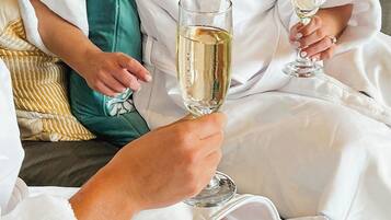 A person in a white robe sitting on a couch with a glass of champagne.