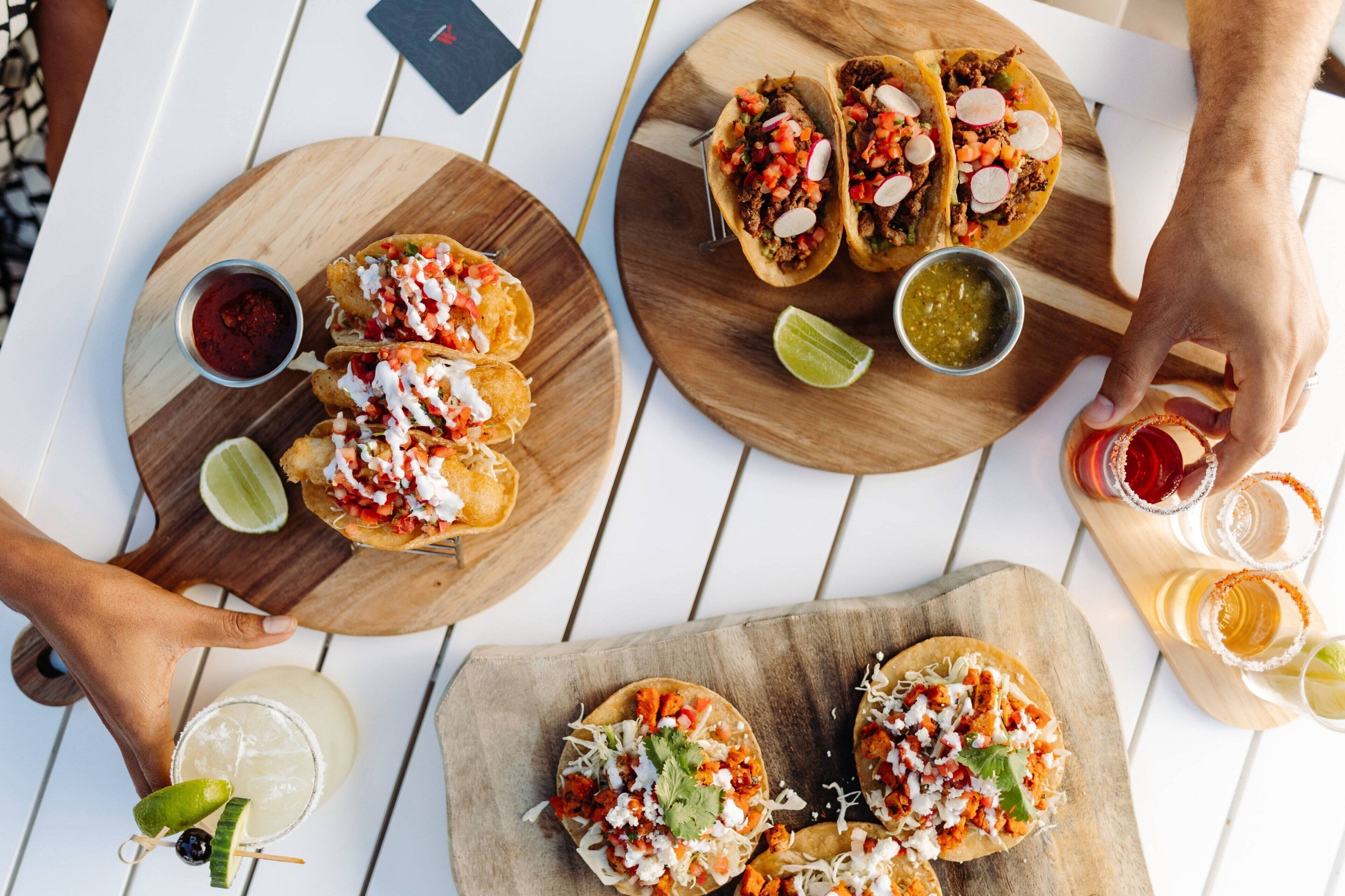 A table with various food items including tacos and nachos, accompanied by drinks and condiments.