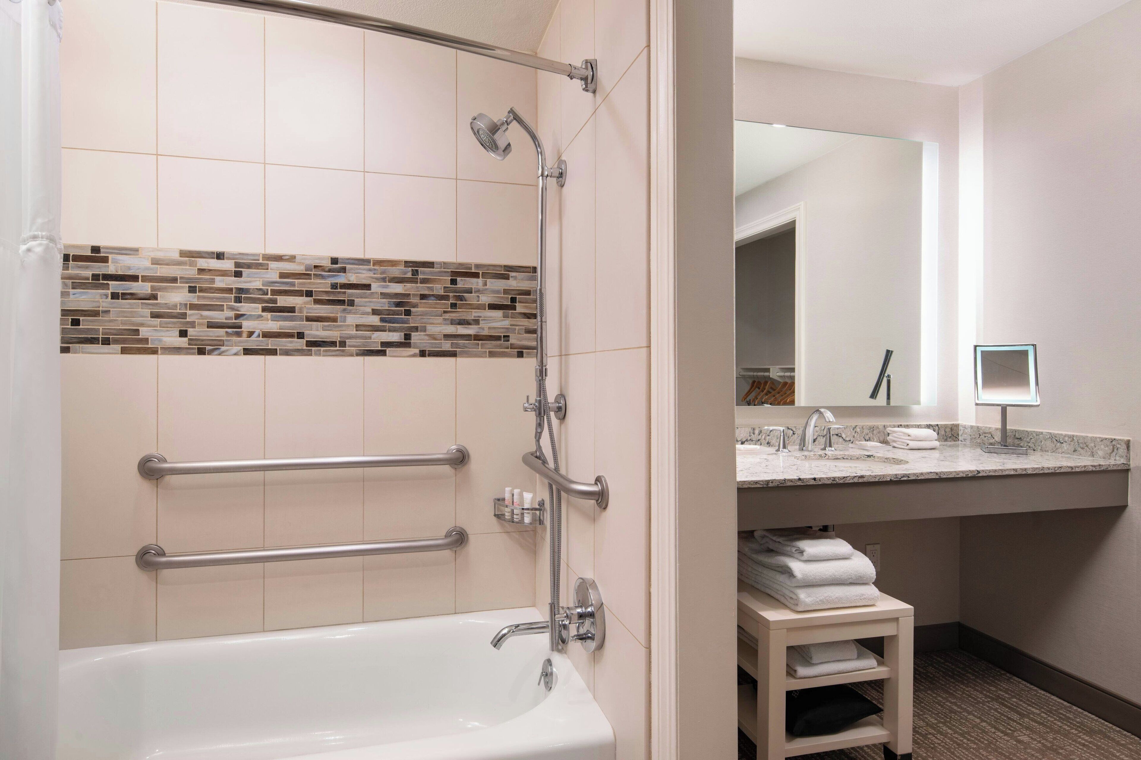 Une salle de bain moderne équipée d’une baignoire, d’une douche et d’un meuble-lavabo avec un évier et un miroir.