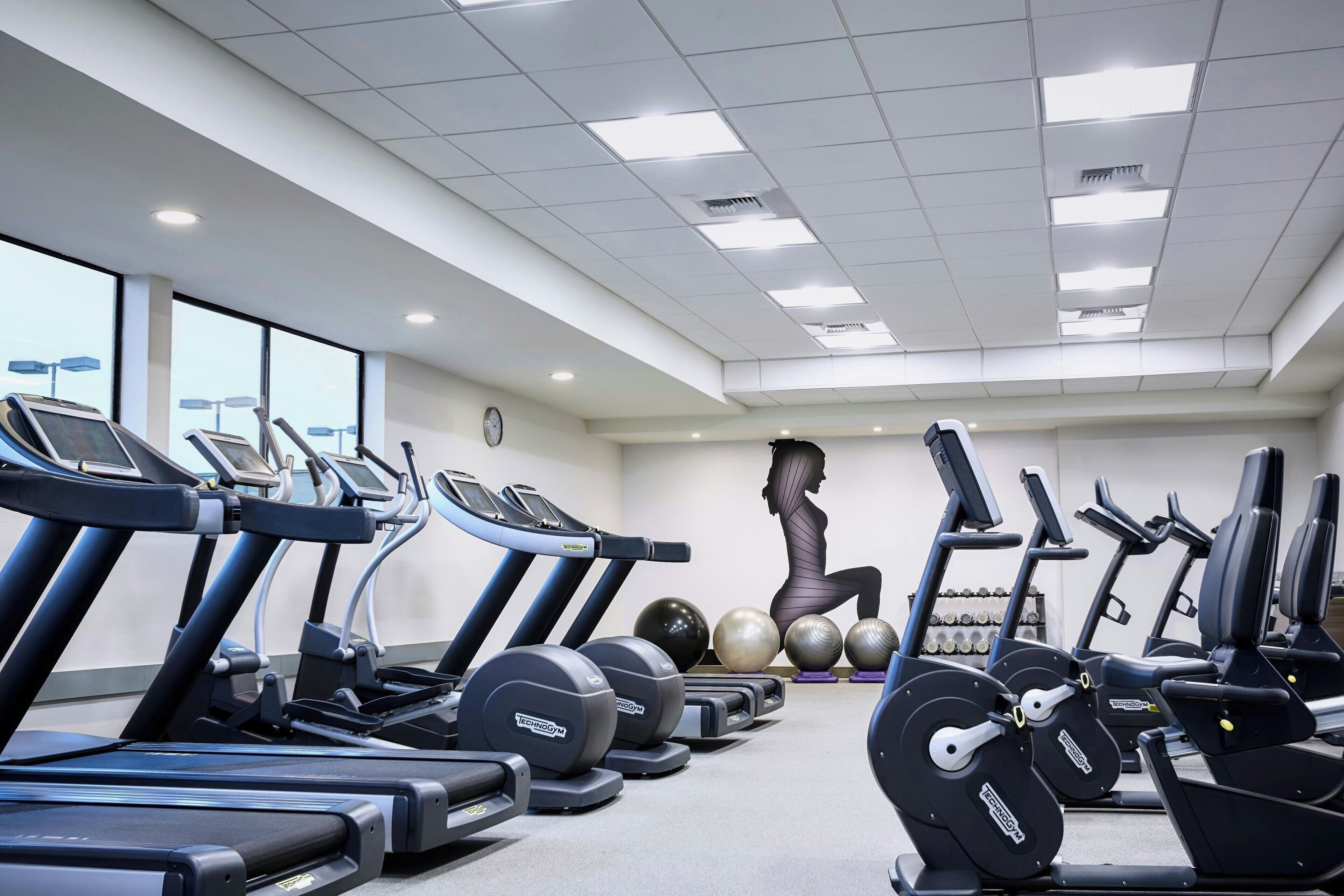 Un gimnasio con cintas de correr, elípticas y pesas sueltas.