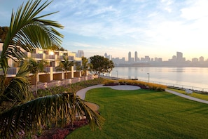 A modern hotel with a view of a city skyline across a body of water.