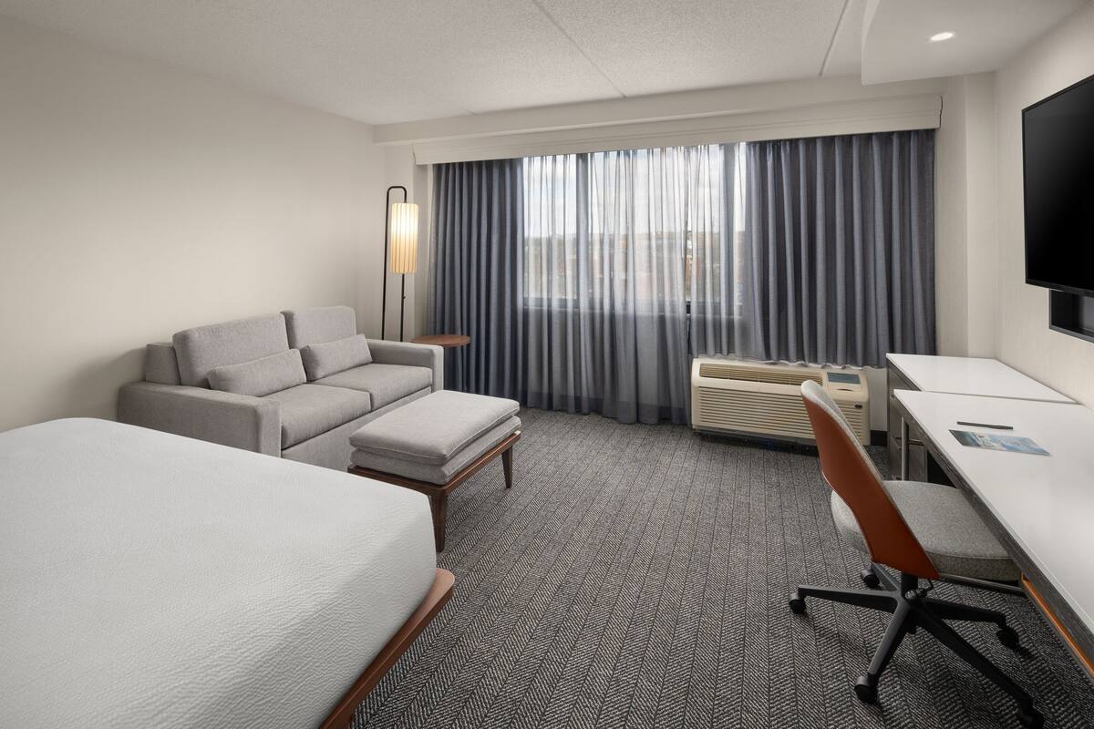 Una habitación de hotel con una cama, un sofá, un escritorio y una silla.