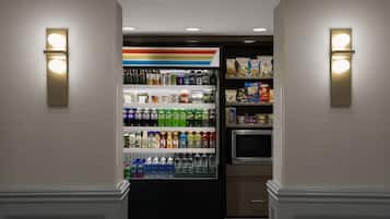 Un minibár de hotel con una variedad de bebidas y aperitivos, como refrescos, agua y bocadillos.