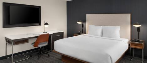 Una habitación de hotel moderna con una cama grande, un escritorio y un televisor de pantalla plana.
