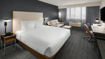 Moderni hotellihuone, jossa on suuri sänky, työpöytä, tuoli ja sohva.