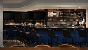 A bar area with a counter, bar stools, and a menu board.