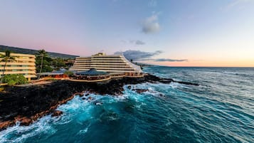 Un hôtel situé sur la côte, composé d’un grand bâtiment et d’une construction plus petite, les deux étant contigus à l’océan.