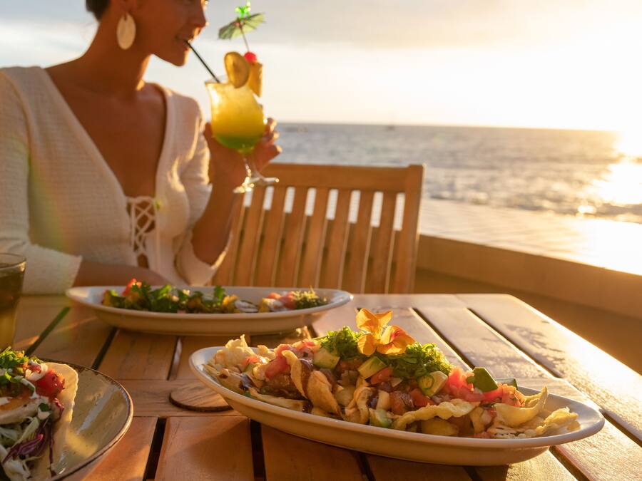 Een eettafel met borden eten en drinken, met uitzicht op de oceaan.