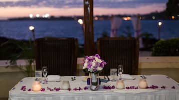 A table set for a meal with a view of the ocean at dusk.