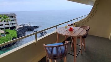 Un balcón con mesa y sillas, con vistas a un litoral rocoso y el océano.