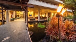 A hotel lobby with a water feature, seating, and a stone wall with a television. - Royal Kona Resort (Kailua-Kona)