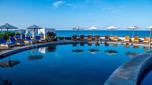 A poolside area with lounge chairs and umbrellas, a clear view of the ocean, and a calm pool reflecting the surroundings. - Royal Kona Resort (Kailua-Kona)