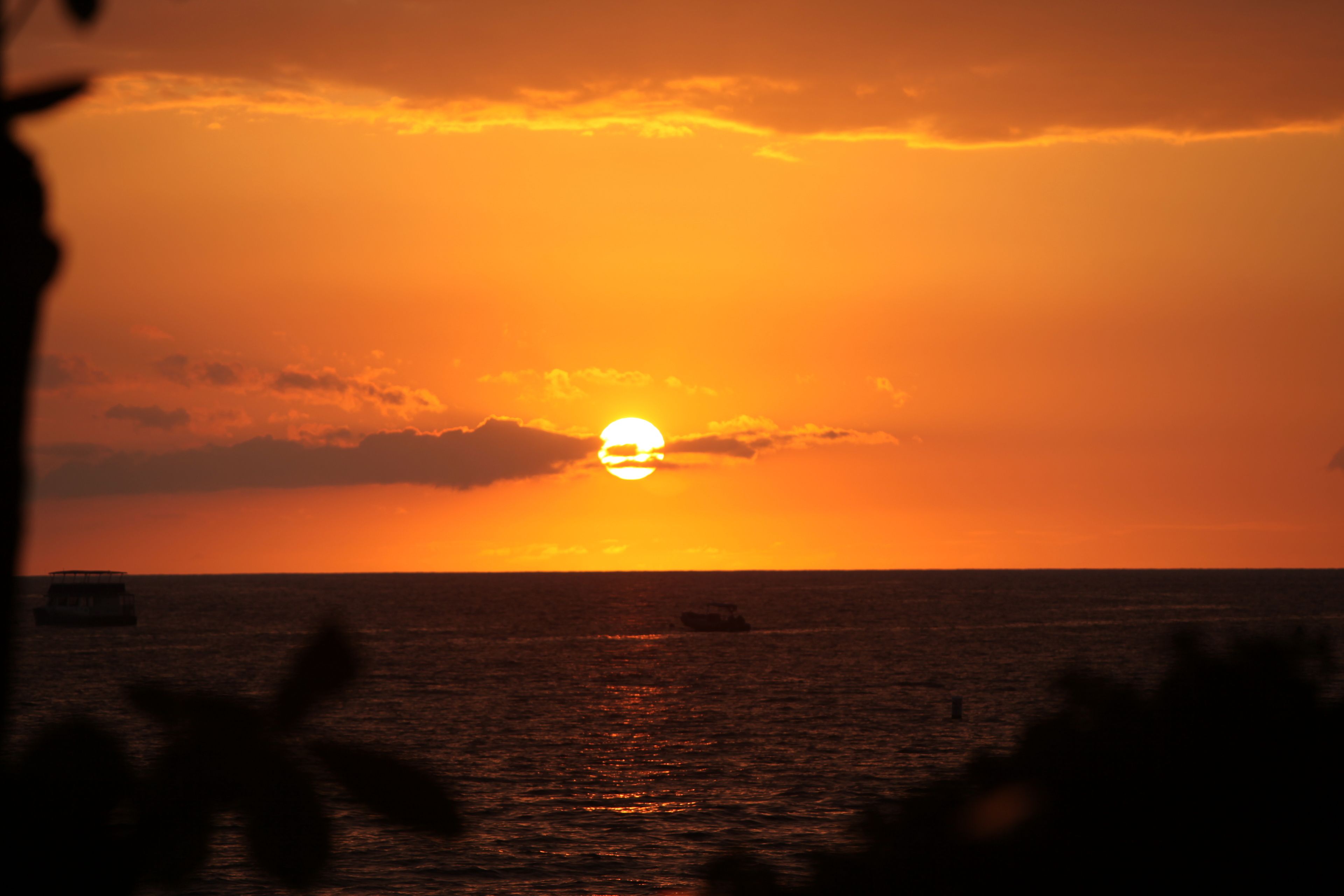 Un atardecer sobre el océano con un barco a lo lejos.