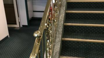 Eine Treppe mit goldener Geländer und schwarzen Stufen mit weißen Punkten.