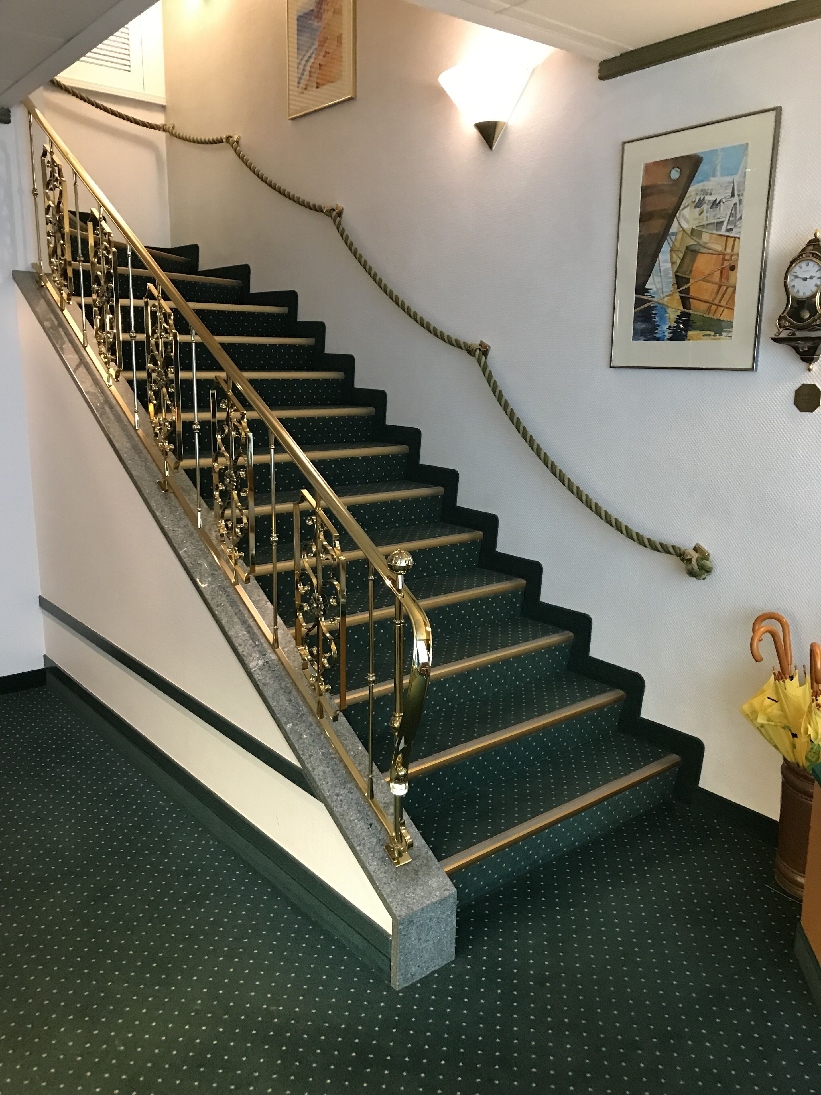 A staircase with a metal handrail and a green carpeted floor.