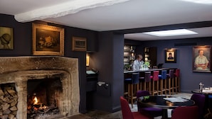 Un rincón acogedor con bar, chimenea, taburetes y una mesa de comedor.