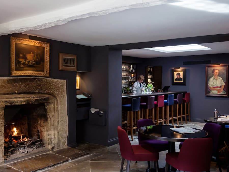 Un rincón acogedor con bar, chimenea, taburetes y una mesa de comedor.
