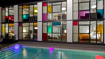 Una piscina al aire libre, sombrillas, sillones reclinables de piscina