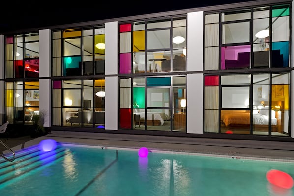 A hotel with a pool area, multiple rooms with beds, and a view of the pool.