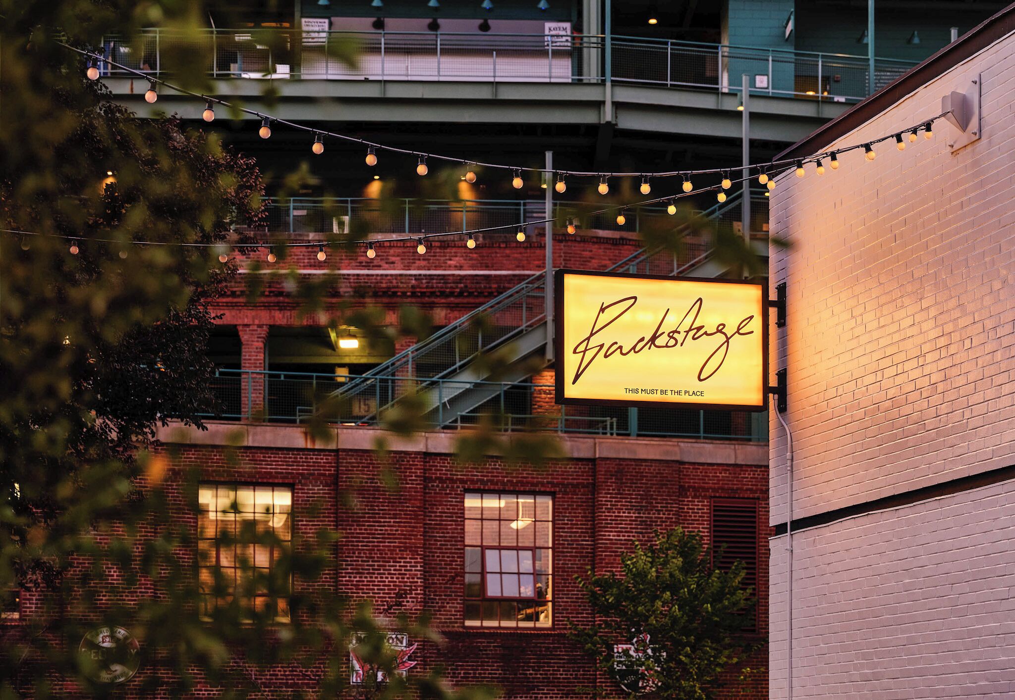 Un edificio de ladrillo con un cartel iluminado que dice 'Backstage'.