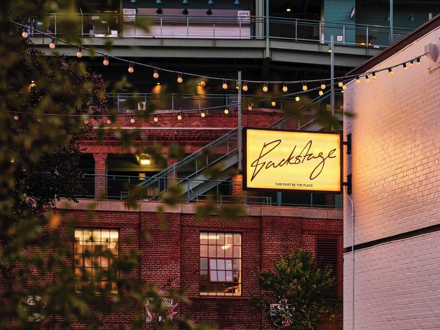 Un edificio de ladrillo con un cartel iluminado que dice 'Backstage'.