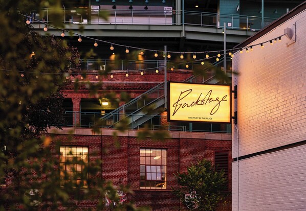 A brick building with a large illuminated sign reading 'Backstage.'