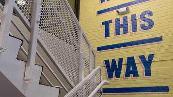 Een trap met een metalen leuning en een muur met de tekst 'WALK THIS WAY'.