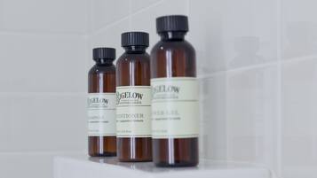 A white shelf with three brown bottles labeled Bigelow Apothecary, containing shampoo and conditioner.