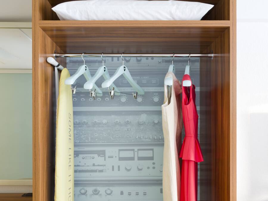 A wooden wardrobe with a hanging rod, a folded dress, and a pair of shoes.