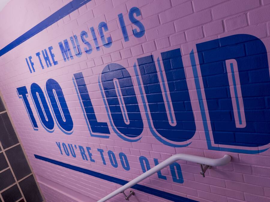 A wall with the text "IF THE MUSIC IS TOO LOUD YOU'RE TOO OLD".