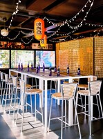 Een bar met een lange tafel, meerdere stoelen en flessen.