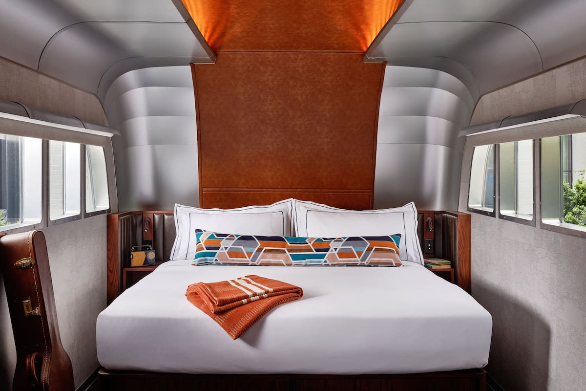 A modern, well-lit bedroom with a large bed, multiple pillows, and a headboard.