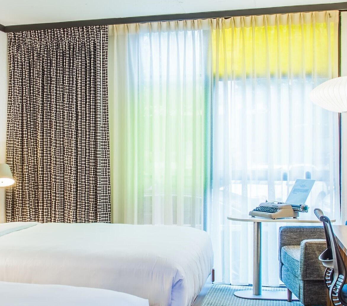 A hotel room with two beds, a desk with a laptop, and a chair.