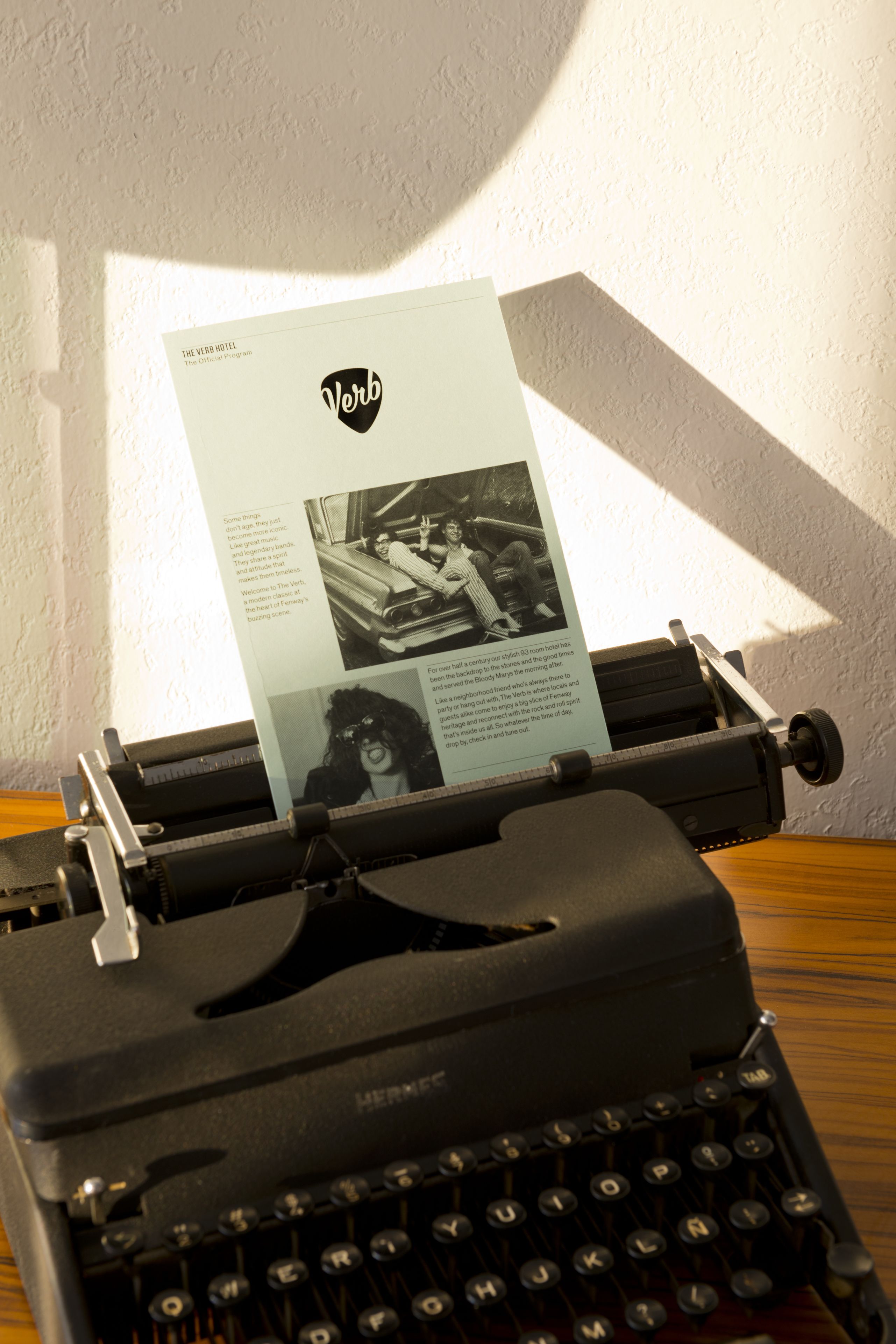 A vintage typewriter with a sheet of paper inserted, displaying text and a photograph.