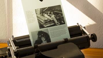 A vintage typewriter with a sheet of paper inserted, displaying text and a photograph.
